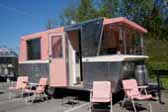 Iconic 1961 Holiday House vintage trailer with matching pink lounge chairs