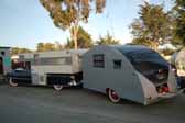 Picture of a vintage cadillac with a camper shell, towing a 1947 komfort koach teardrop trailer