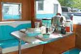 Photo of restored dinette area with blue and white upholstered bolsters in Aloha trailer