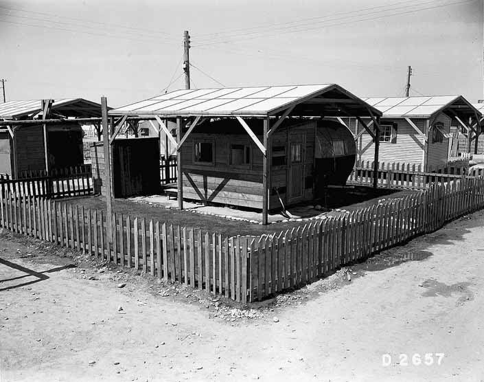 Government photo shows a 1940's vintage travel trailer with an attached wooden shack at the Project Hanford Trailer City