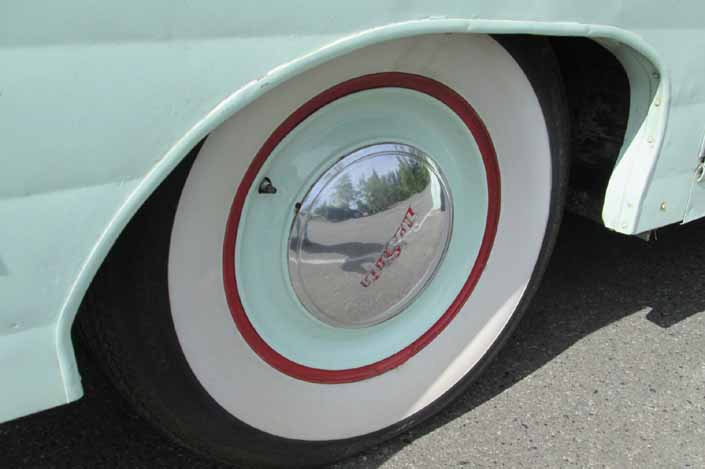 Photo shows an example of a vintage trailer with wheels that have a unique painted full hubcap and wide ww tires