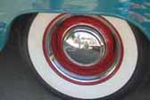 Image shows a restored vintage trailer with wheels painted red, and a chrome hubcap and beauty ring
