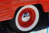Great example of an orange vintage trailer wheel with a chrome hubcap and wide whitewall tire