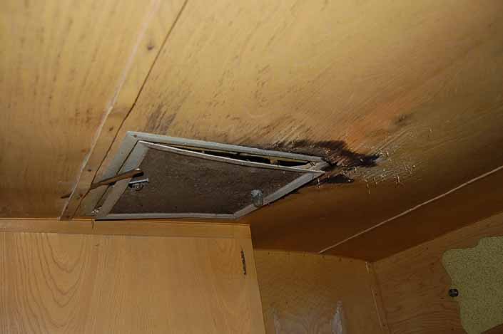 Water damaged ceiling paneling in vintage Shasta trailer in storage yard