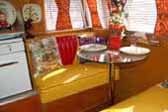 Photo shows sunny yellow dining area in a 1955 Shasta Trailer