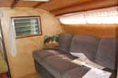 Photo of gorgeous wood paneling and beautifully upholstered couch in 1956 Campmaster Teardtop trailer