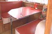 Red and white reupholstered bench seating in 1956 Shasta Trailer dining area