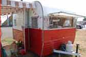 Picture shows a very clean vintage Aloha travel trailer painted in classic red and white color scheme