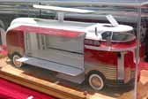 Photo of a detailed scale model of a GM Parade of Progress Futurliner bus with the roof light bar raised and the side panels open to showcase the exhibits inside