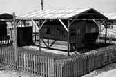 Government photo shows a 1940's vintage travel trailer with an attached wooden shack at the Project Hanford Trailer City