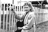 Historical photo shows a pretty woman dressed up and painting her picket fence, at the Hanford Trailer Camp in Washington