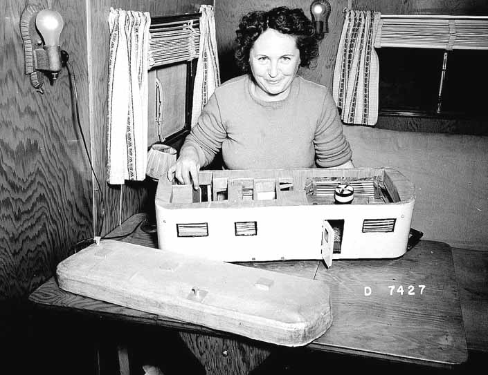 Government photo shows a woman proudly displaying her scale model travel trailer, at Project Hanford Trailer City in Washington