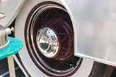 Photos shows old vintage wire wheels painted maroon and with a small hubcap, mounted on a vintage trailer from the 1950's
