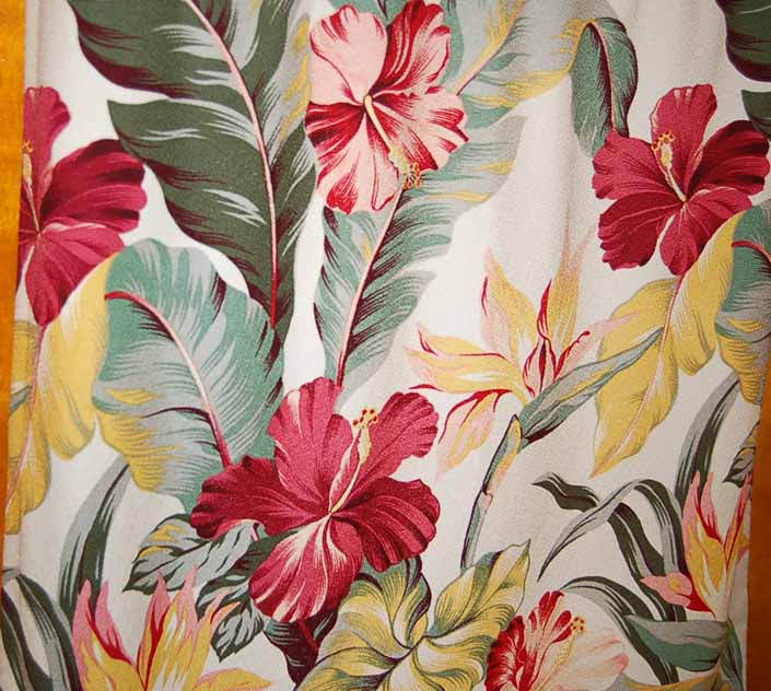 This photo shows a swatch of retro fabric with a hawaiian tropical flowers design on a white background, for your vintage trailer