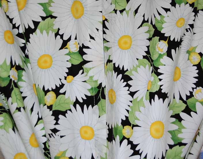 This photo shows a swatch of retro fabric with Bright Daisies on a Black Background pattern, for your vintage trailer
