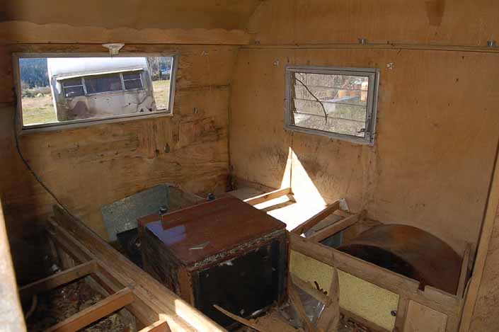 Tired Shasta Compact trailer parked in a vintage trailer StorageYard has a trashed interior needing restoration